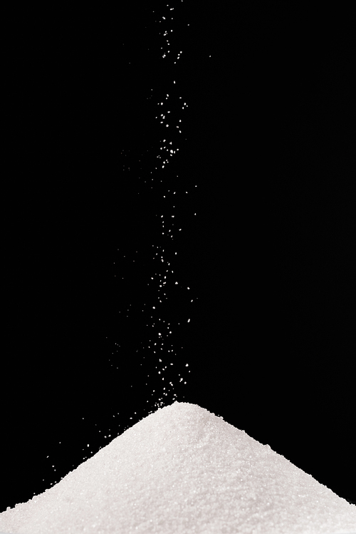 white sugar falling on pile isolated on black