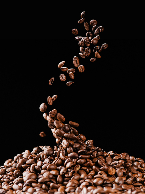falling coffee beans on pile isolated on black
