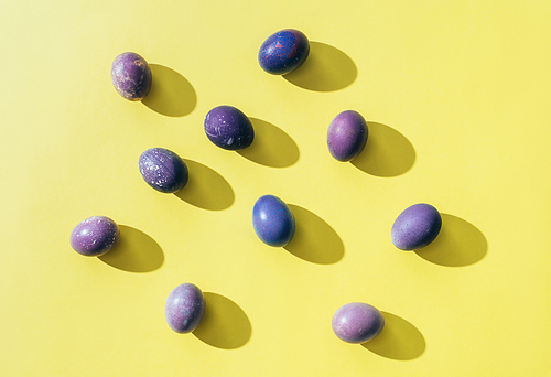 top view of purple painted easter eggs on yellow with shadows