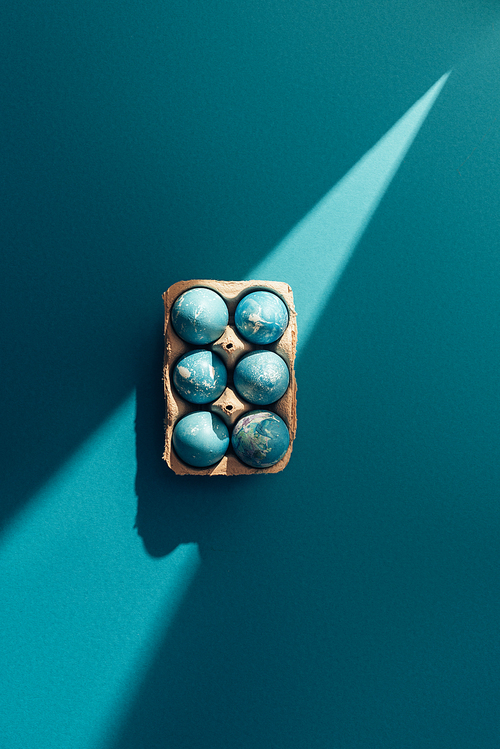 top view of blue easter eggs in tray| on blue with sunbeam