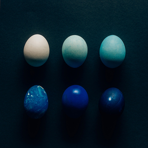 collection of six colored painted easter eggs on dark surface