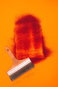 top view of red sand for decoration and brush isolated on orange