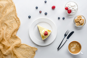 top view of piece of cake with berries and coffee on white tabletop