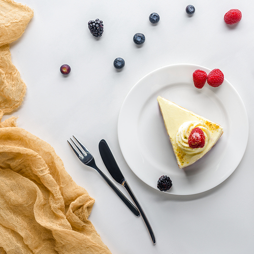 top view of piece of cake with berries on plate on white table