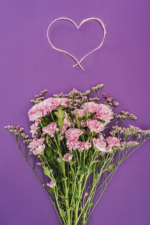 bouquet of beautiful pink flowers and heart-shaped rope on violet