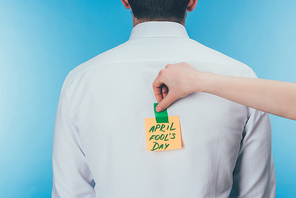 cropped shot of woman putting note with april fools day lettering on males back| april fools day concept