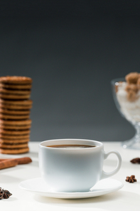 Hot black coffee in cup on table with cookies and spices