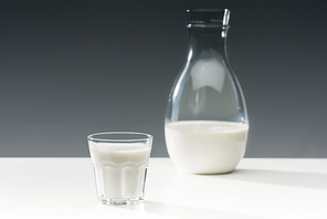 Milk in glass and bottle on table on grey background