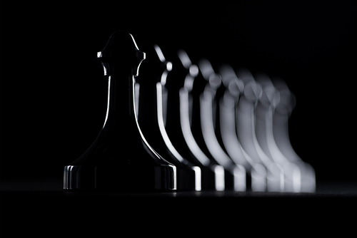 silhouettes of row of chess figures isolated on black, business concept