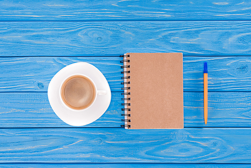 top view of coffee cup, textbook and pen on blue wooden planks