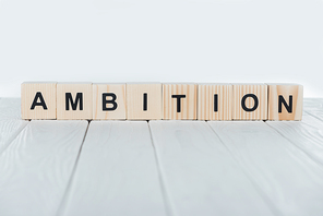 close up view of ambition word made of wooden cubes on white wooden tabletop