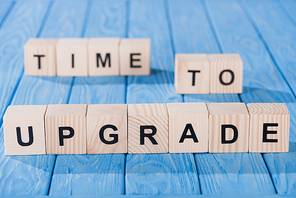 close up view of arranged wooden blocks into time to upgrade phrase on blue wooden surface