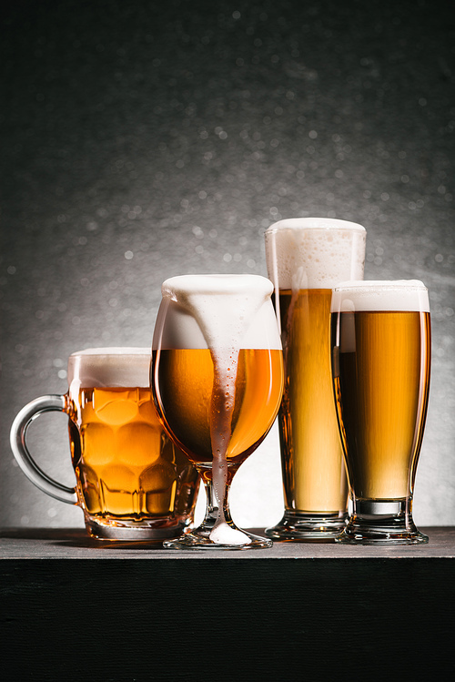 close up view of mugs of cold beer with foam on grey background