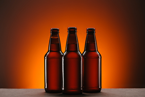 close up view of arranged bottles of beer on orange backdrop