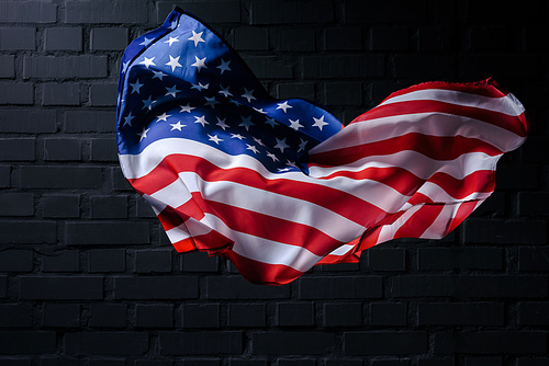 dynamic waving united states flag in front of black brick wall, Independence Day concept