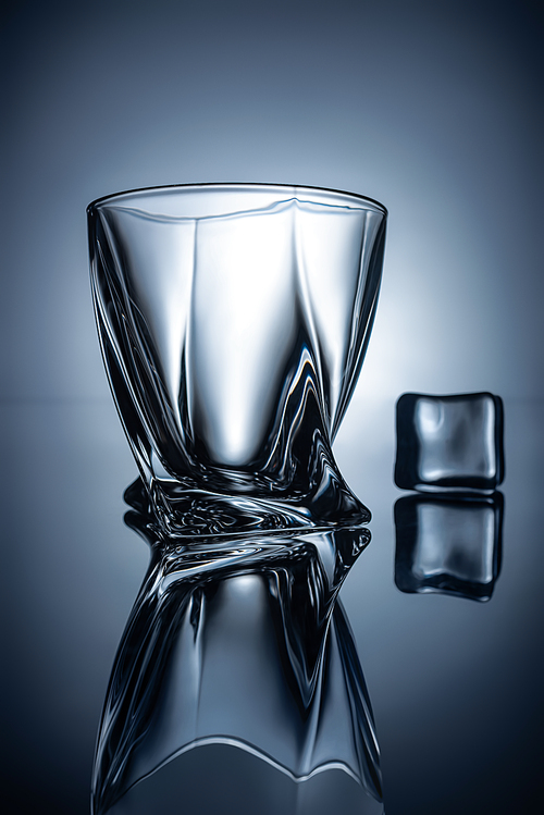 silhouettes of empty whiskey glass and ice cube, on grey