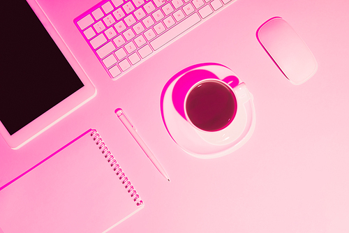 pink toned picture of coffee cup, digital tablet, pen, textbook, computer keyboard and mouse on table