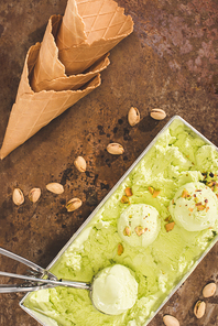 top view of pistachio ice cream with scoop and ice cream cones on table