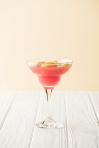 close up view of tasty summer alcohol cocktail on white wooden tabletop on peach background