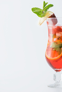 close up view of summer strawberry cocktail with ice, mint, lemon and orange pieces isolated on white