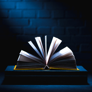 open book on stack of books on dark tabletop