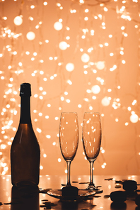 close up view of bottle of champagne and empty glasses in bokeh style