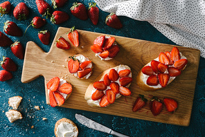 top view of fresh strawberries by wooden board with summer sandwiches