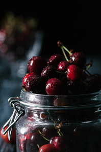 close-up view of ripe wet sweet cherries in glass jar