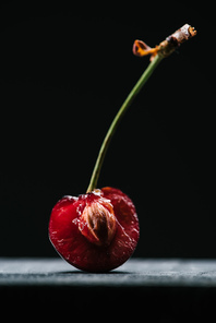 close-up view of half of fresh ripe cherry on black