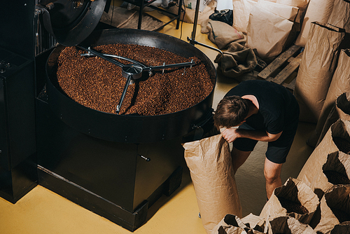 Man filling paper bag with freshly roasted coffee beans