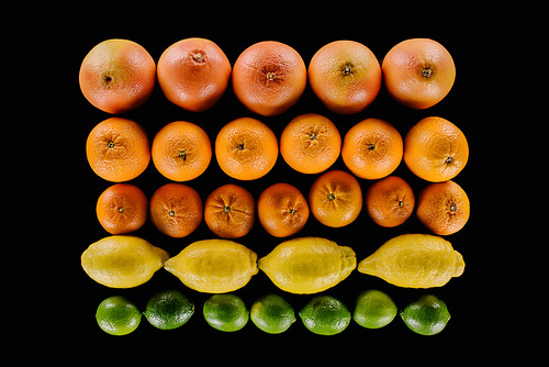 top view of composition of various ripe citrus fruits in rows isolated on black