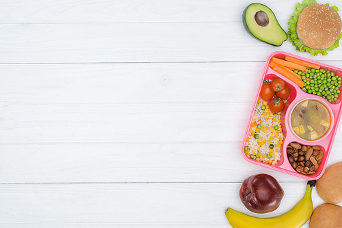 top view of tray with kids lunch for school and fruits on wooden table