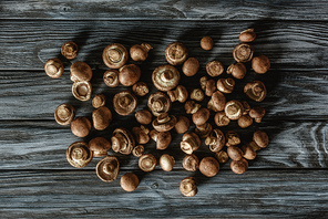 top view of pile of raw brown champignon mushrooms on wooden surface
