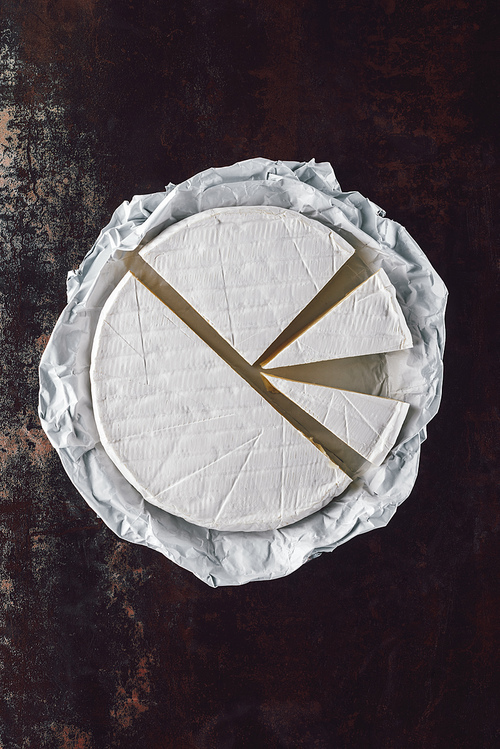 top view of cut camembert cheese on dark surface