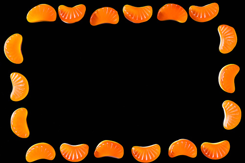 top view of frame of jelly candies in shape of tangerine pieces isolated on black