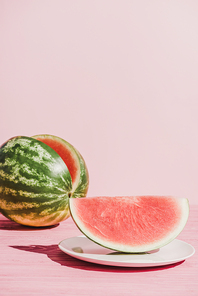 close up view of slice of watermelon on plate on pink background