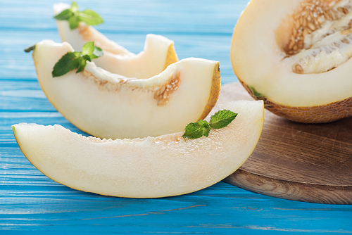 close-up view of sliced sweet ripe melon with mint on blue wooden surface