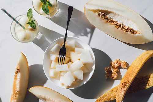 top view of delicious sliced melon, glasses with refreshing beverage and seeds on white