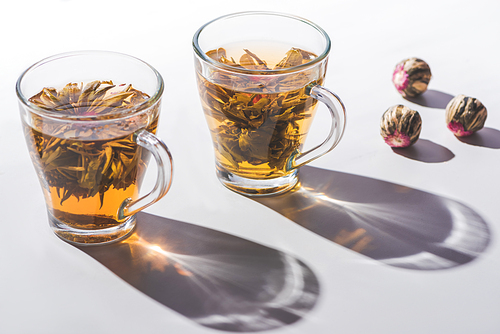 two cups of chinese flowering tea with tea balls on table