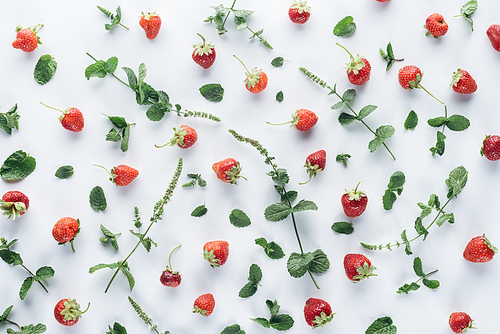 top view of fresh strawberries with mint leaves on white tabletop