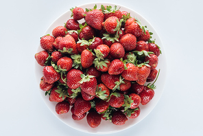 top view of ripe strawberries in bowl on white tabletop