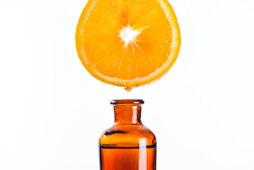 aromatic juice of orange piece dripping into bottle of natural herbal essential oil isolated on white