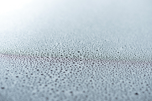 close up view of water drops on grey surface as background