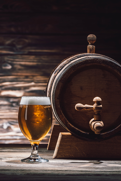 glass of fresh beer and beer barrel on wooden table, oktoberfest concept