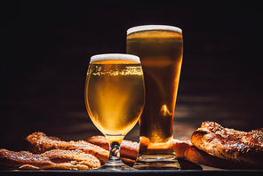 glasses of beer and tasty pretzels on wooden table, oktoberfest concept
