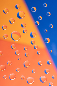 close-up view of transparent water drops on colorful background