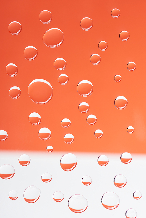 close-up view of transparent calm droplets on white and orange background