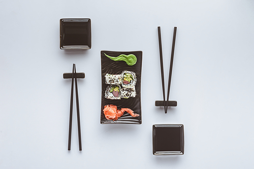 top view of gourmet sushi with chopsticks, ginger and wasabi isolated on white