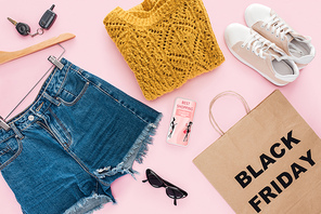 top view of stylish clothes, smartphone with best shopping app and bag with black friday sign