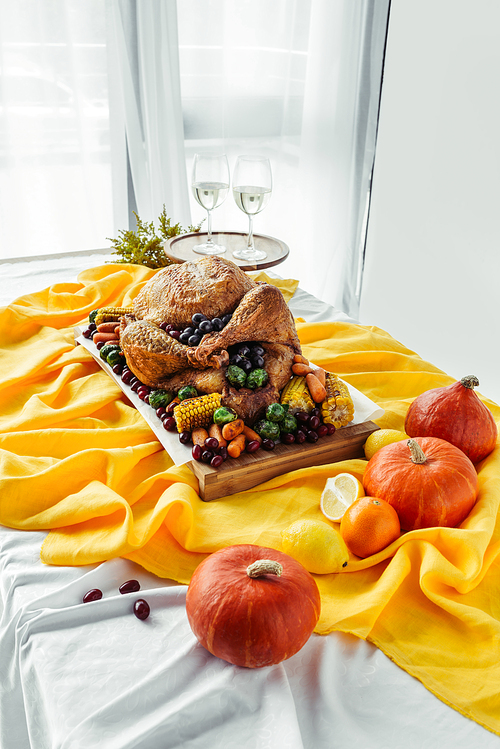 close up view of festive thanksgiving dinner table set with glasses of wine, roasted turkey and vegetables on tabletop with tablecloth